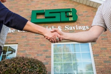 Image of people shaking hands in-front of a banking center