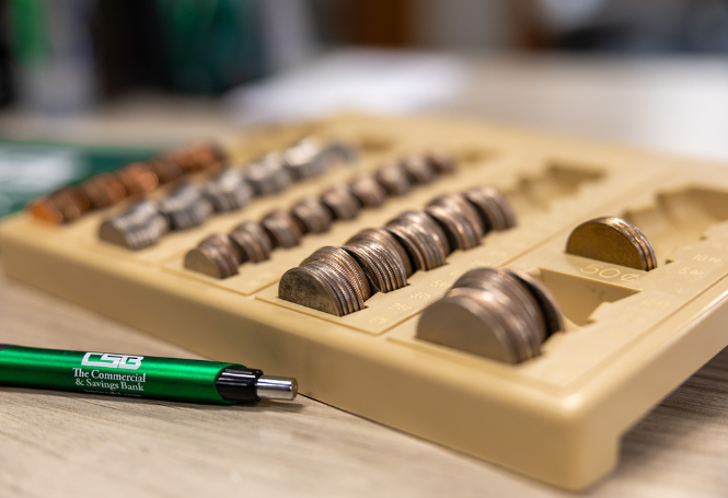 Organized coin tray with CSB branded pen on desk.