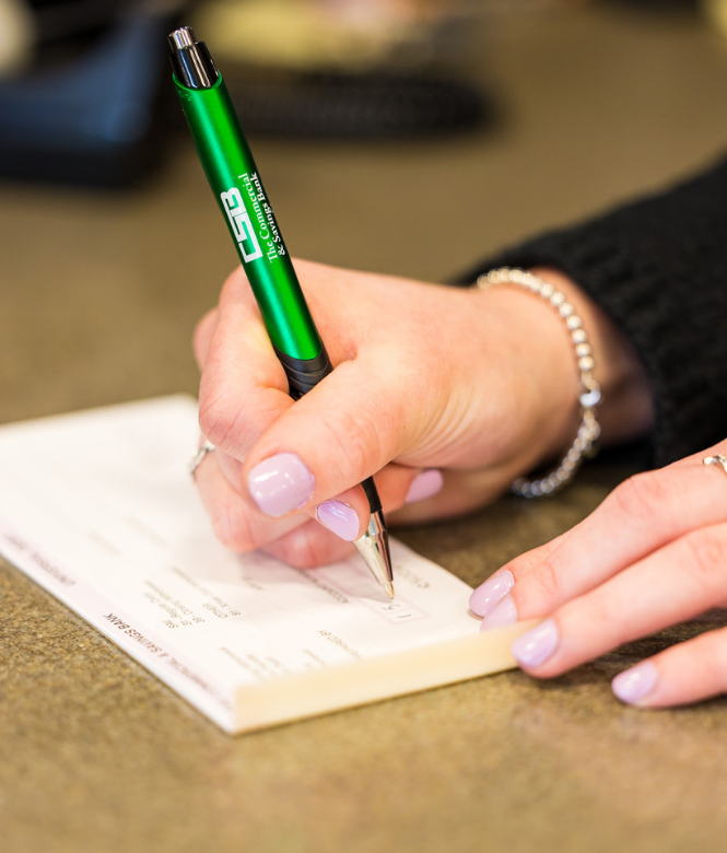 Customer filling out a deposit slip with CSB pen at counter