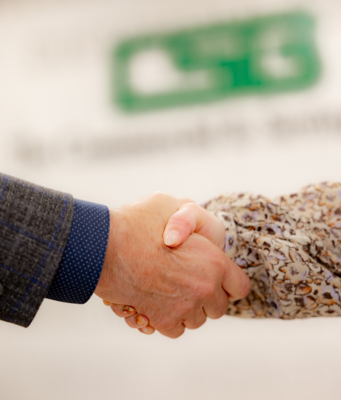 Two people shaking hands in front of CSB branded wall.