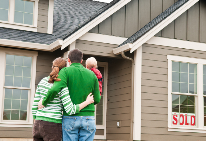 Family standing together outside their new home, facing the front door.