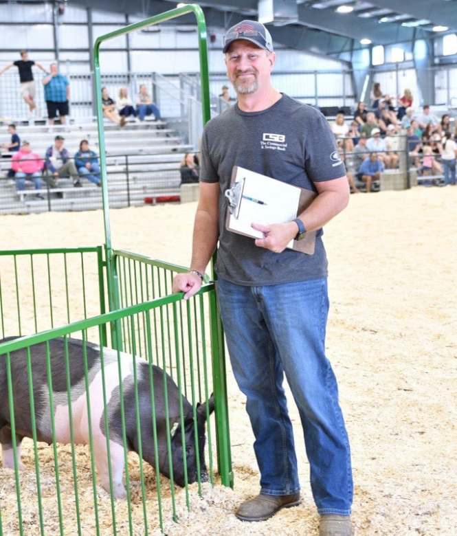 CSB employee Jason smiling while posing with pig at Holmes County Fair
