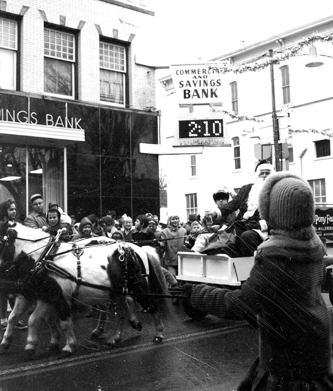 Vintage photo of Christmas parade passing by old CSB building in downtown Millersburg.