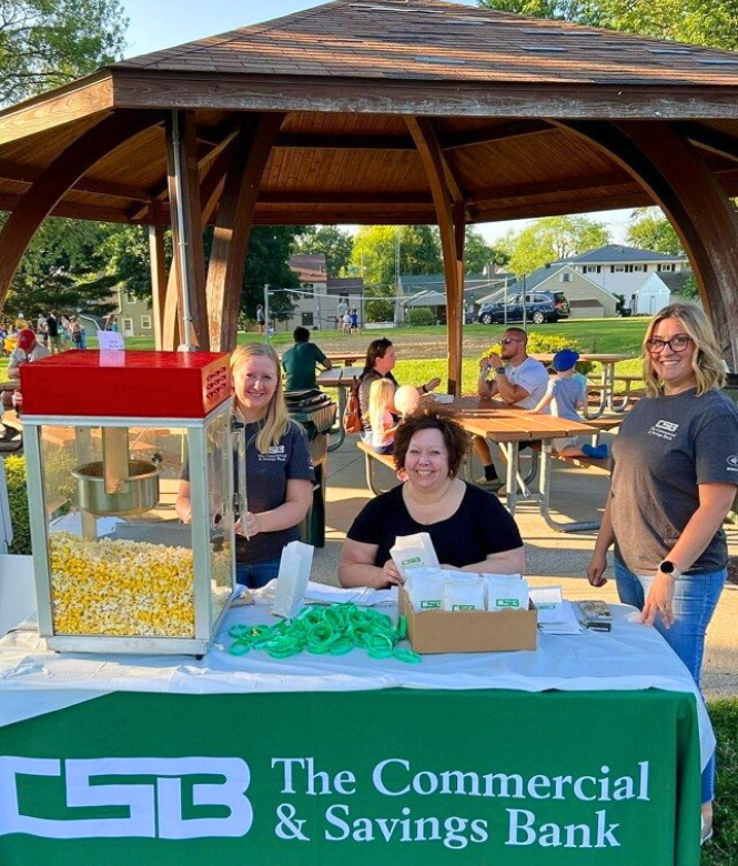 CSB employees handing out popcorn and goodies at a community park event