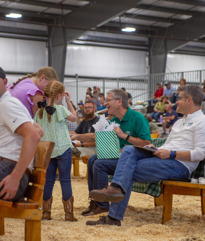 CSB president and employee seated at Holmes County Fair animal showing, greeting young participant