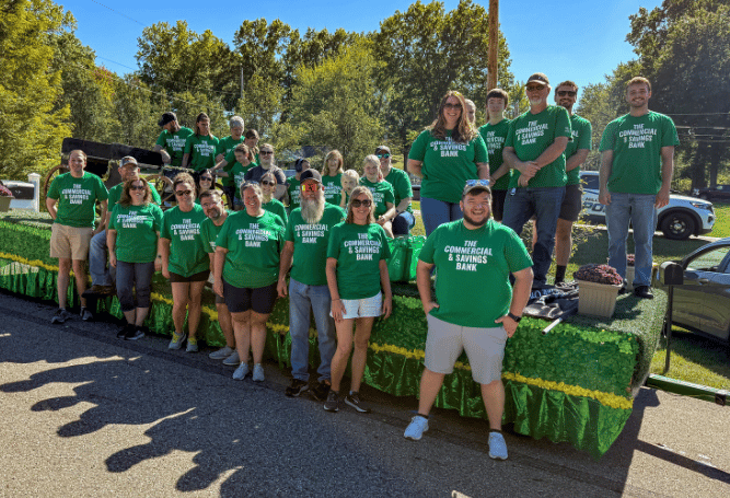 Commercial & Savings Bank employees and family members gather outdoors for a community volunteer event.