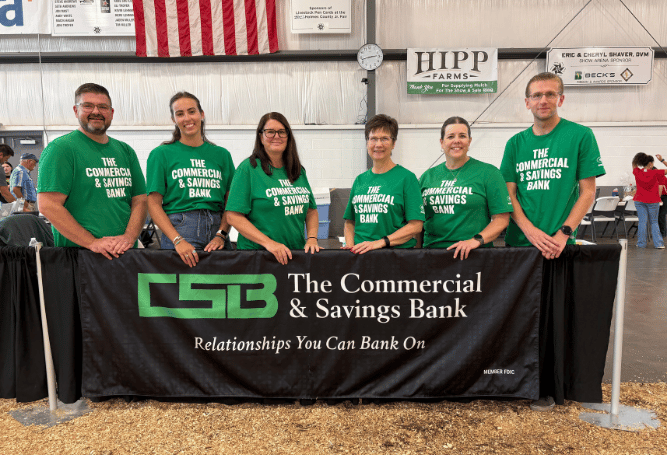Commercial & Savings Bank team members stand behind a CSB display table at a community event.