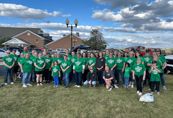 Commercial & Savings Bank employees and family members gather outdoors for a community volunteer event.