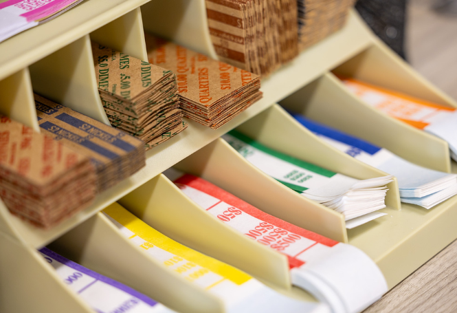 Assorted bank coin rolls and cash bands in labeled compartments