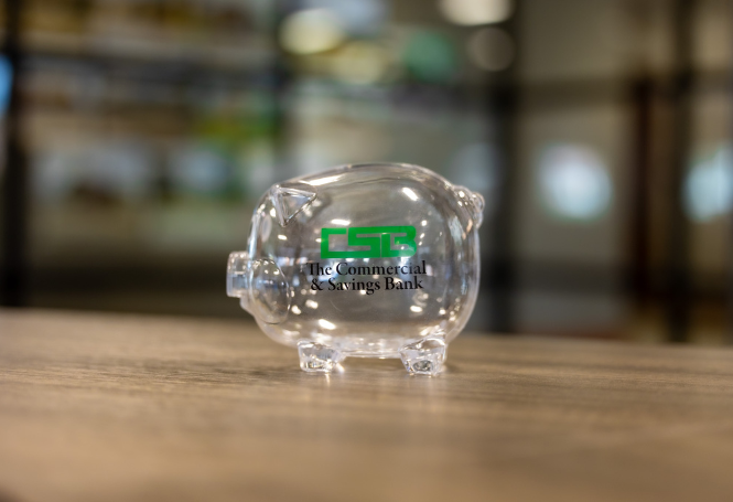Transparent piggy bank with CSB logo displayed on tabletop