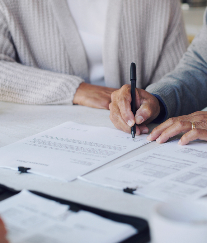 Couple reviewing and signing financial documents.