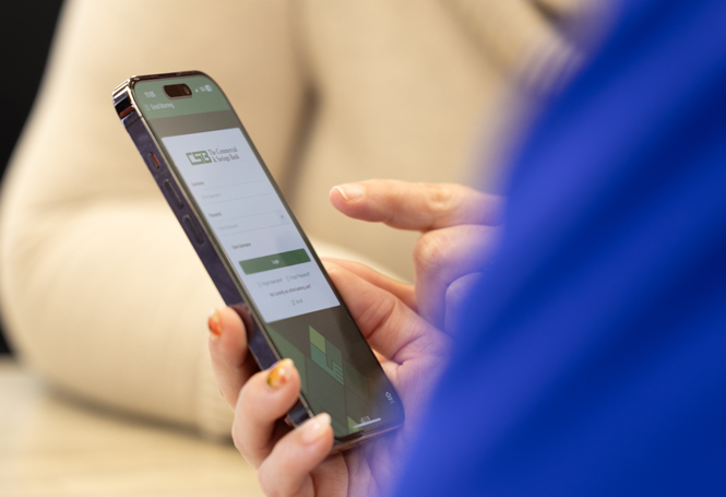 Hand holding a phone displaying the CSB mobile banking login screen.