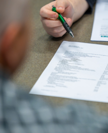 Person pointing at a printed document during a discussion or review.